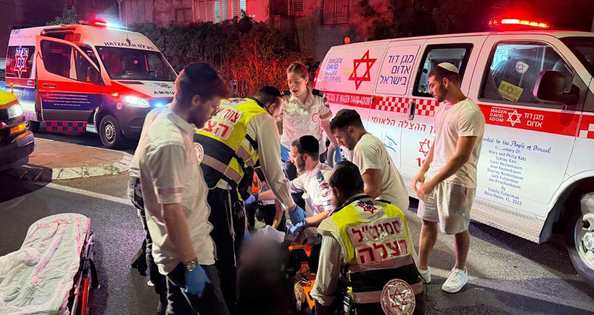 צוות הצלה וצוות מגן דוד אדום מטפלים בפצוע על הכביש מאחוריהם ניידות מגן דוד אדום וניידת הצלה