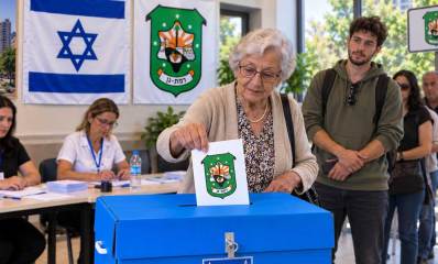 בחירות לכנסת ברמת גן. איור AI. אישה משלשלת מעטפה לקלפי. מימינה תור של מצביעים. מאחור יושבים חברי ועדת הקלפי.