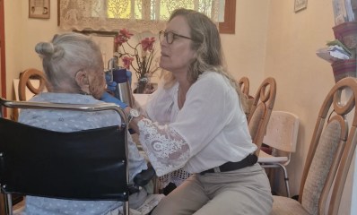 רופאה מתנדבת מטפלת בניצולת שואה בכסא גלגלים.