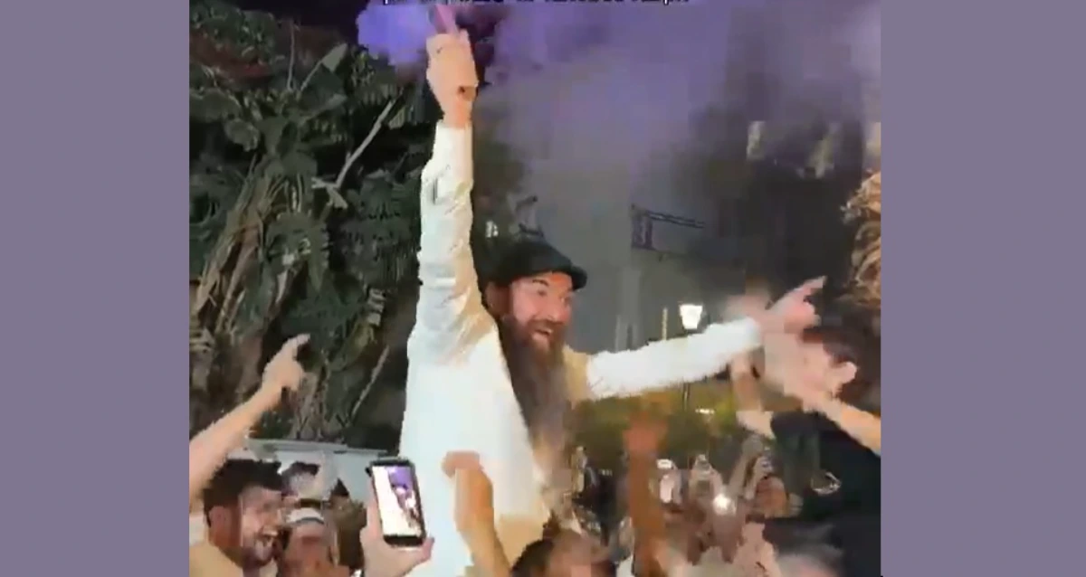 הרב יוסף דלויה בחגיגות מונף על כתפיים של אדם אחר עם עשן סגול בידו